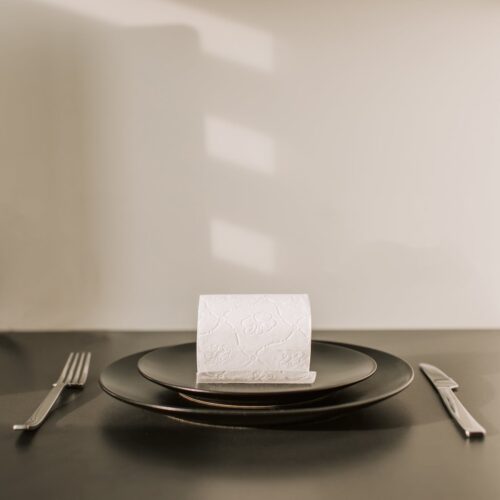 toilet paper roll on dish with fork and knife